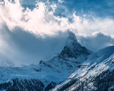 snowy mountain peaks under cloudy sky in sunlight