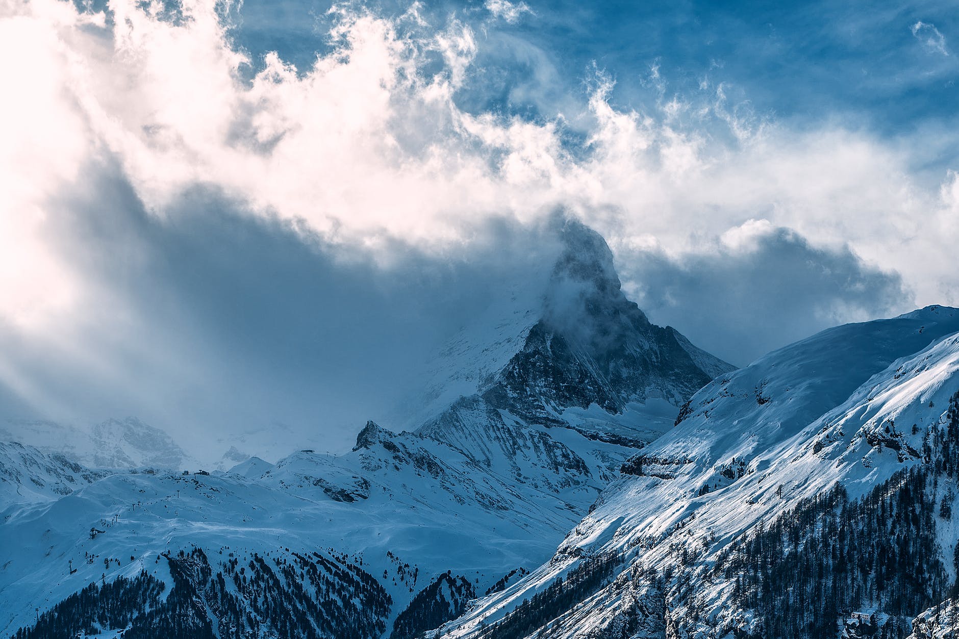 snowy mountain peaks under cloudy sky in sunlight